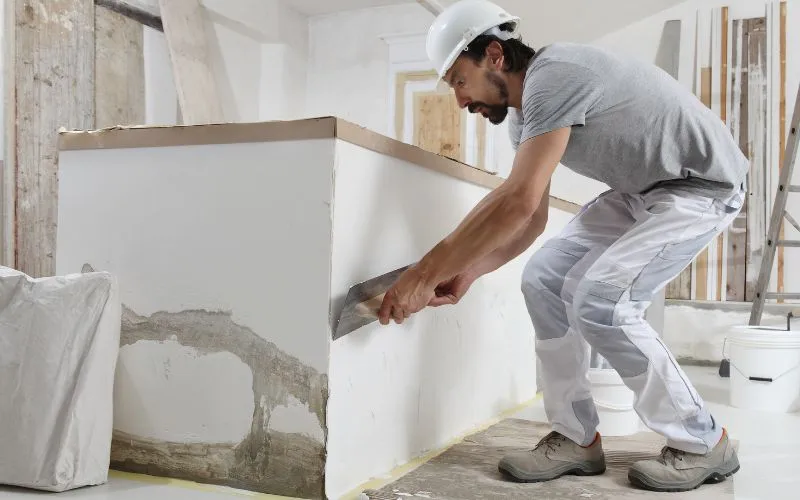 Artisan en train d'appliquer de l'enduit - Transformation complète d'un intérieur